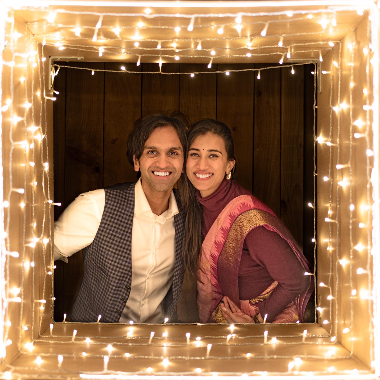 Yaduraj and Shreyasi, smiling, framed by fairy lights